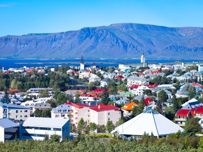 Uitzicht over Reykjavik met kleurrijke daken, Hallgrímskirkja en de bergen op de achtergrond.