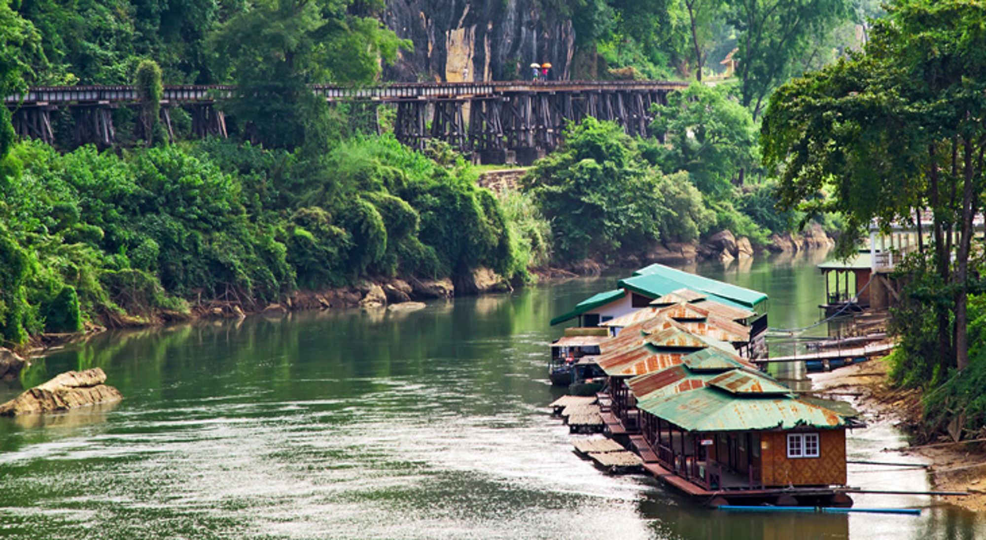 Kanchanaburi Drijvende huisjes op de River Kwai met de houten Death Railway-brug in Kanchanaburi, Thailand.