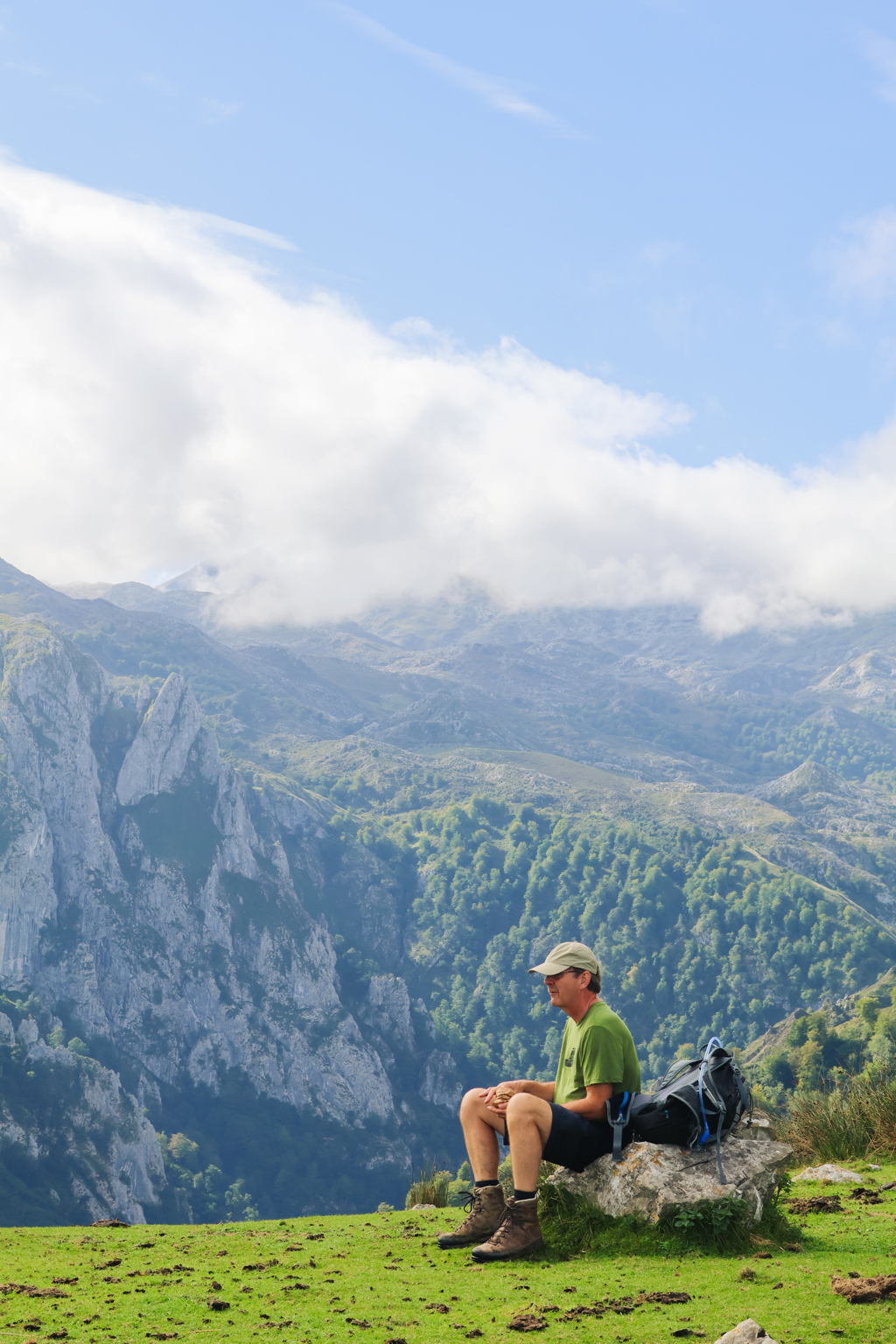 Wandelaar met rugzak rust uit met uitzicht op de bergen van Picos de Europa in Spanje.