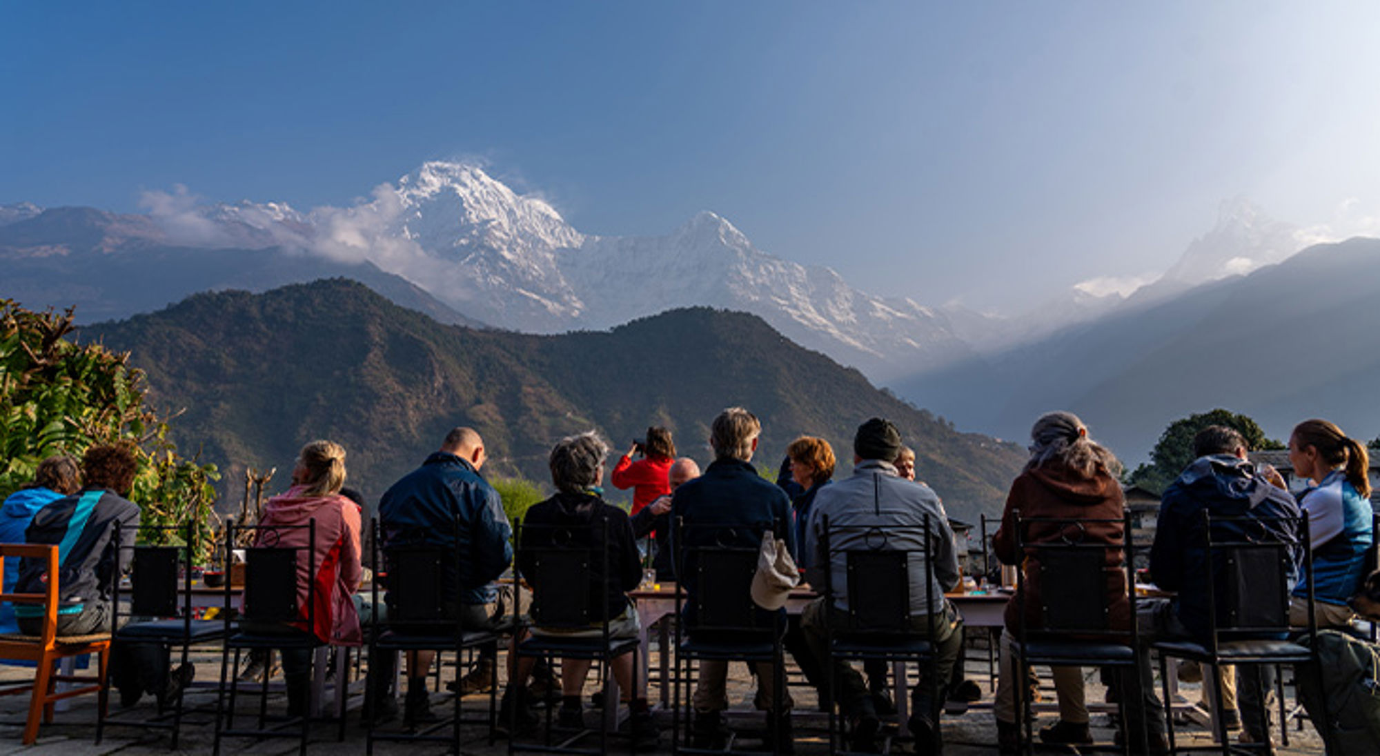 Ontbijt Ghandruk Reizigers genieten op een terras van uitzicht op besneeuwde Himalaya-bergen bij zonsopkomst.