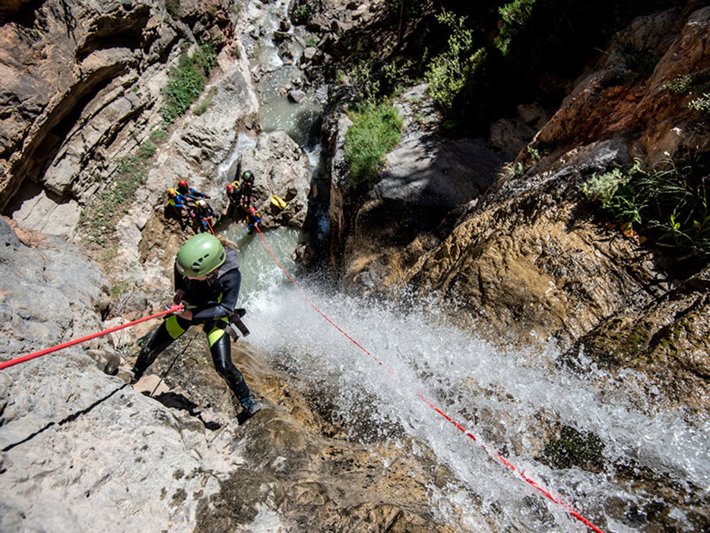 Canyoning in de Écrins in Frankrijk: deelnemer daalt met touw af langs waterval in smalle kloof.
