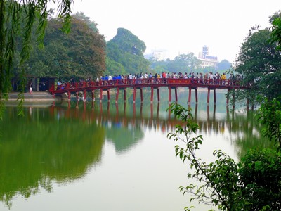 Rode houten brug met wandelaars over het Hoan Kiem-meer in Hanoi, Vietnam.