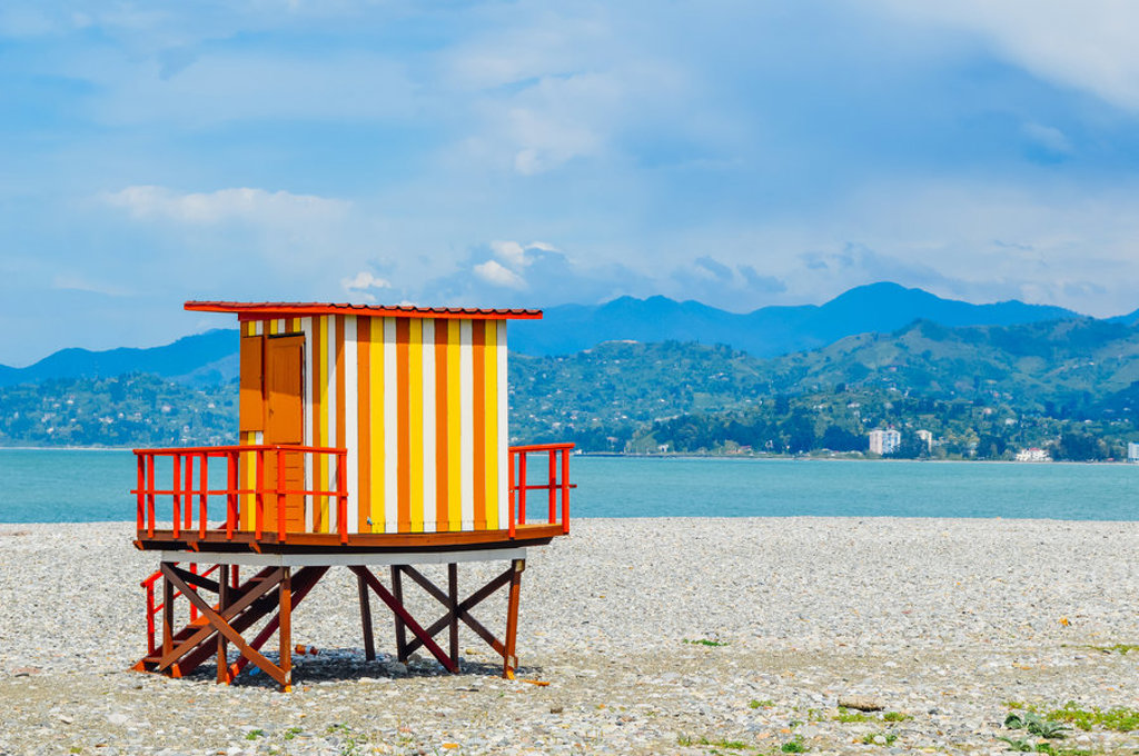 Gekleurde strandwachtpost aan de Zwarte Zee in Georgië, met bergen op de achtergrond.