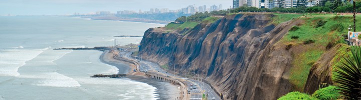 Kustkliffen en boulevard van Miraflores in Lima, met uitzicht op de Stille Oceaan en moderne hoogbouw.