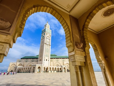 Hassan II-moskee in Casablanca, gezien door een boog met de minaret tegen een blauwe lucht.