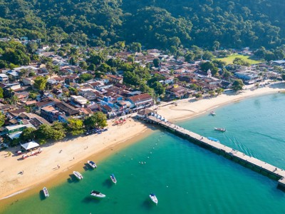 een kustplaats met strand, pier en boten in helderblauw water op de route Brazilië en Buenos Aires.