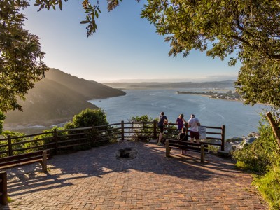 Uitzichtpunt over de Knysna Lagoon langs de Tuinroute in Zuid-Afrika, met reizigers bij zonsondergang.