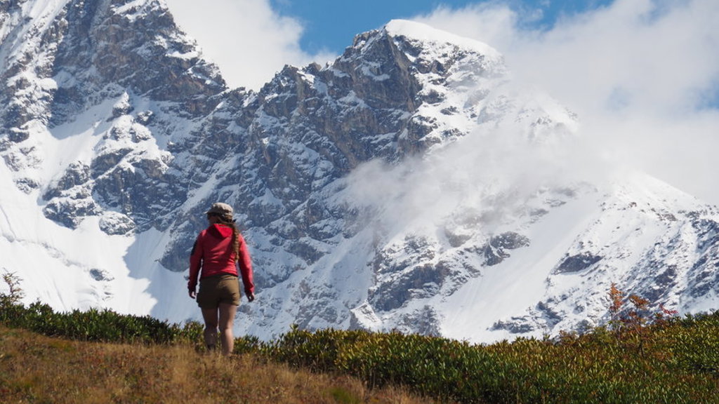 Wandelaar in de Kaukasus met besneeuwde bergtoppen op de achtergrond tijdens een groepsrondreis Georgië.