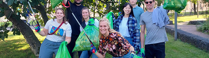 Sawadee-collega’s ruimen zwerfafval op tijdens World Cleanup Day en houden volle groene vuilniszakken vast.