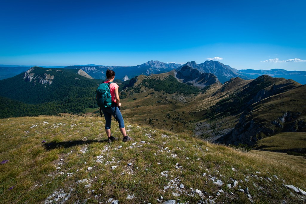 Wandelaar met rugzak kijkt uit over berglandschap in Bosnië en Herzegovina tijdens een wandelvakantie.