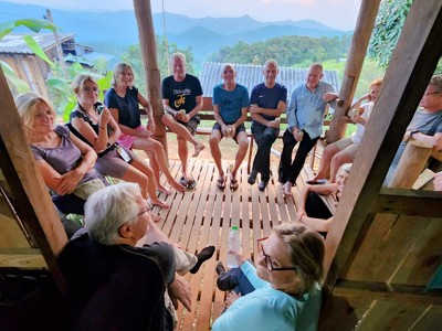 Reisgroep ontspant op een houten veranda met uitzicht op de bergen in Noord-Thailand.
