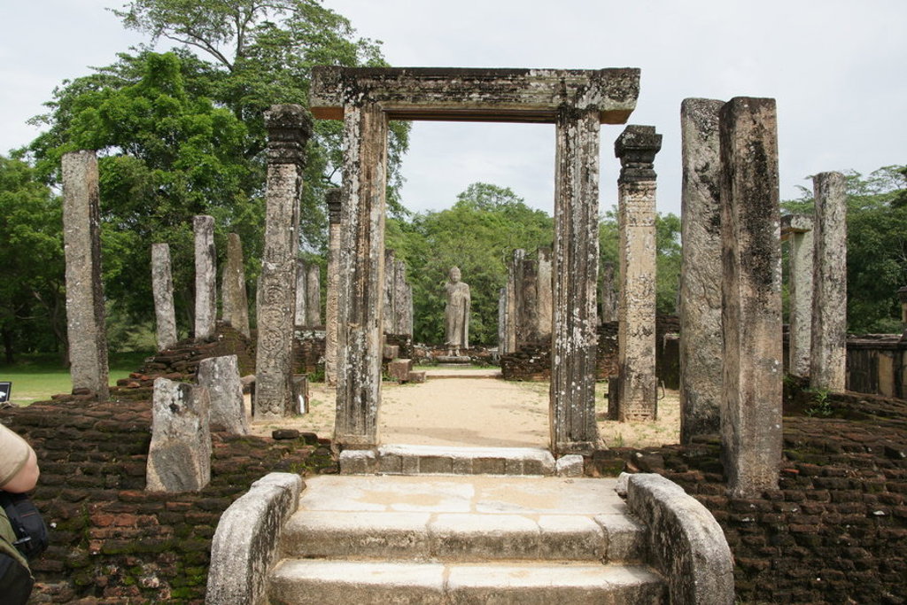 Ruïnes van het koninklijk paleis in Polonnaruwa, Sri Lanka, met stenen zuilen en Boeddhabeeld.