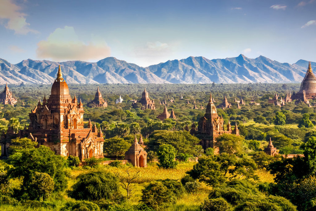 Tempels en pagodes in Bagan, Myanmar, met groen landschap en bergen op de achtergrond.