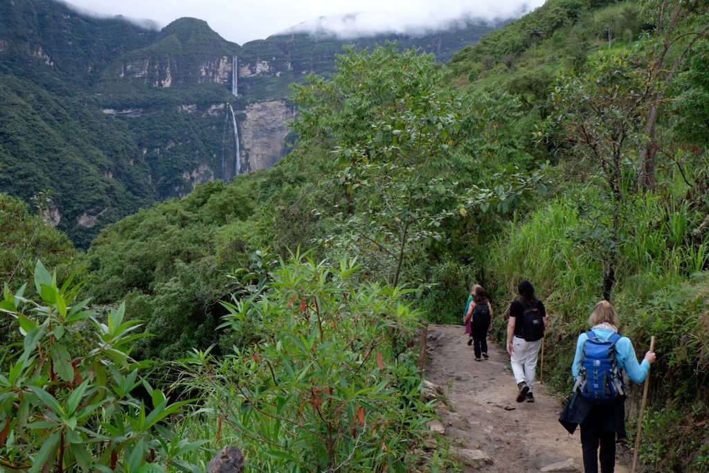 Wandelaars op bergpad met uitzicht op waterval in Noord-Peru.