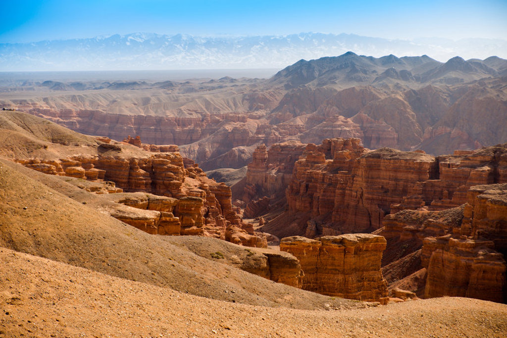 Panoramisch uitzicht op de Charyn Canyon met rode rotsformaties en bergen, tijdens groepsrondreis Zijderoute.