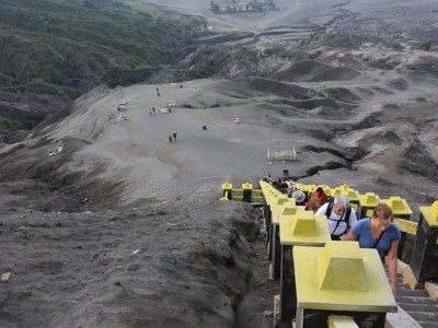 Toeristen beklimmen een trap door een grijs vulkanisch landschap op Java tijdens de route Sumatra, Java en Bali.