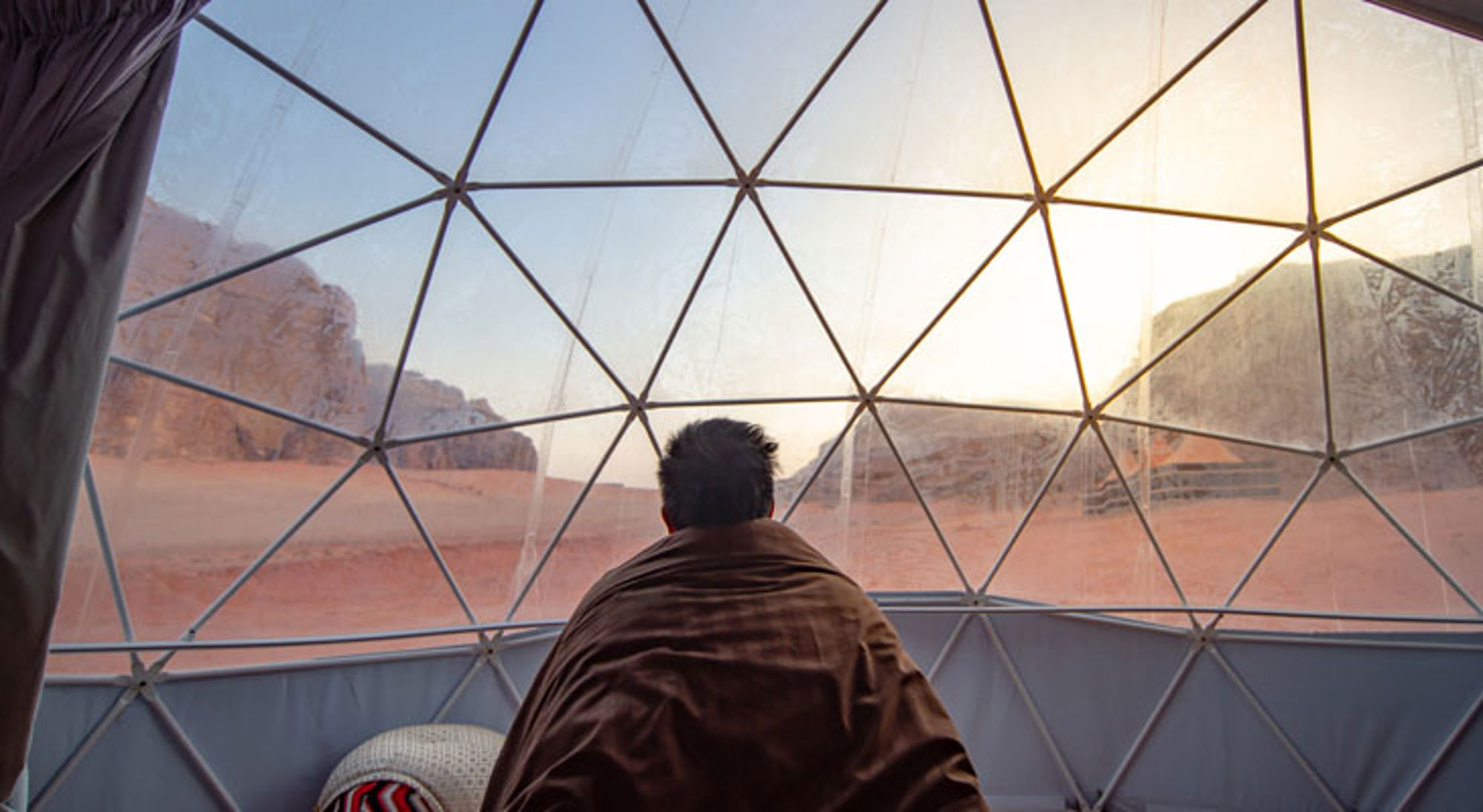 Overnachting Wadi Rum Jordanië Uitzicht op de Wadi Rum-woestijn in Jordanië vanuit een transparante koepeltent bij zonsopkomst.