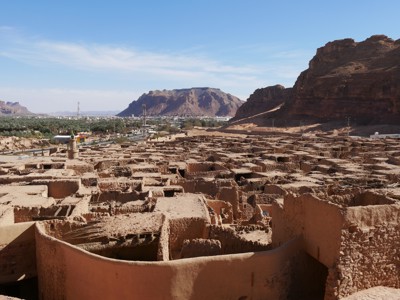 Uitzicht over de lemen ruïnes van het oude AlUla, met palmoase en rotsbergen op de achtergrond in Saoedi-Arabië.