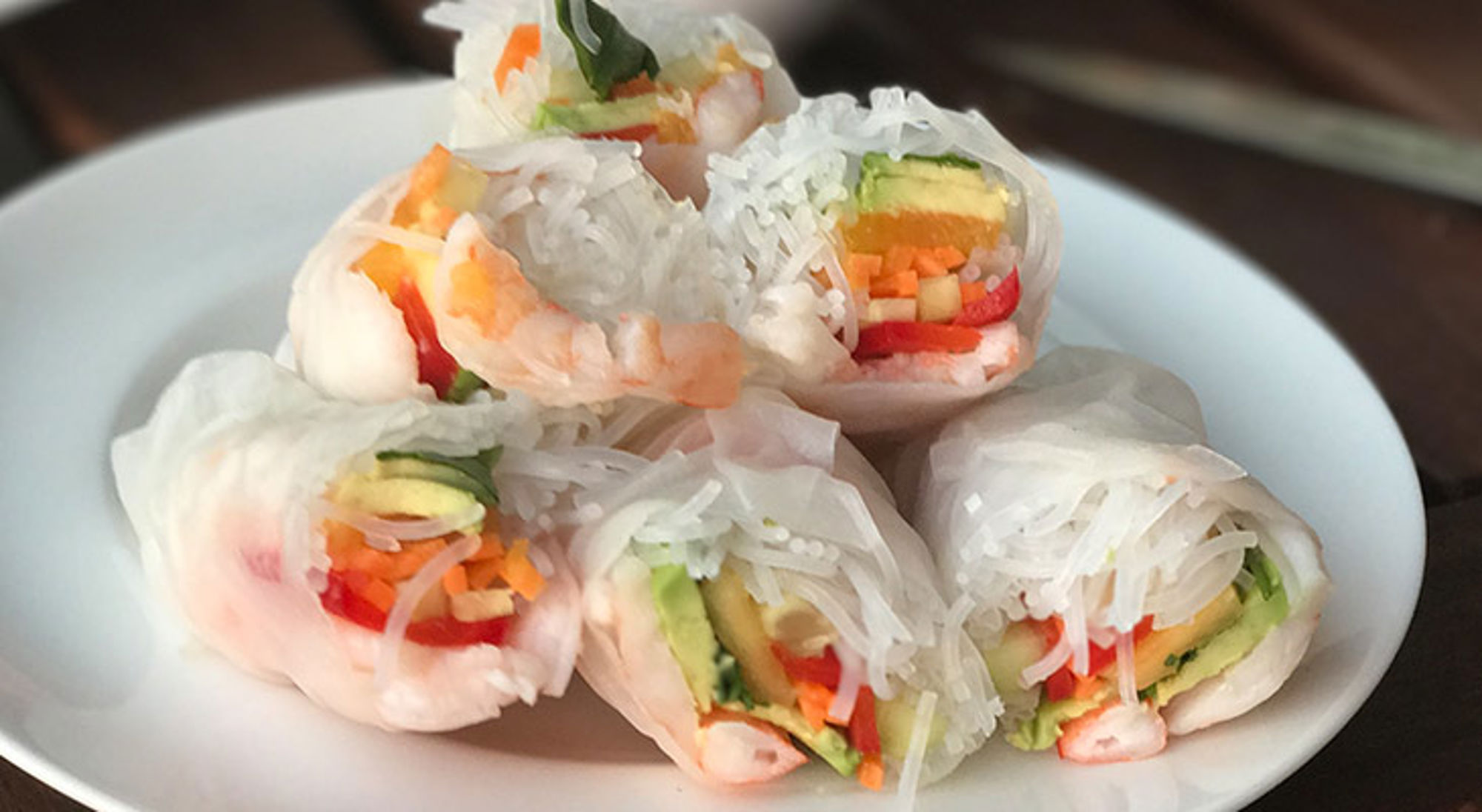 Verse Vietnamese springrolls met garnalen, rijstnoedels en groenten op een wit bord.