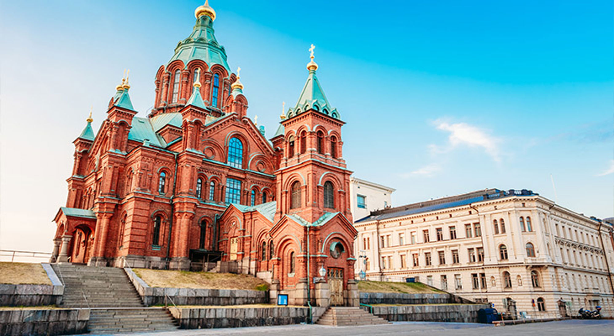 Oespenski Kathedraal in Helsinki Uspenski-kathedraal in Helsinki met rode baksteen en groene koepels onder een heldere blauwe lucht.