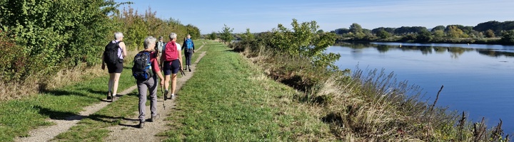 Wandelaars op een dijkpad langs een rivier in Nederland tijdens de Dutch Mountain Trail wandelvakantie.
