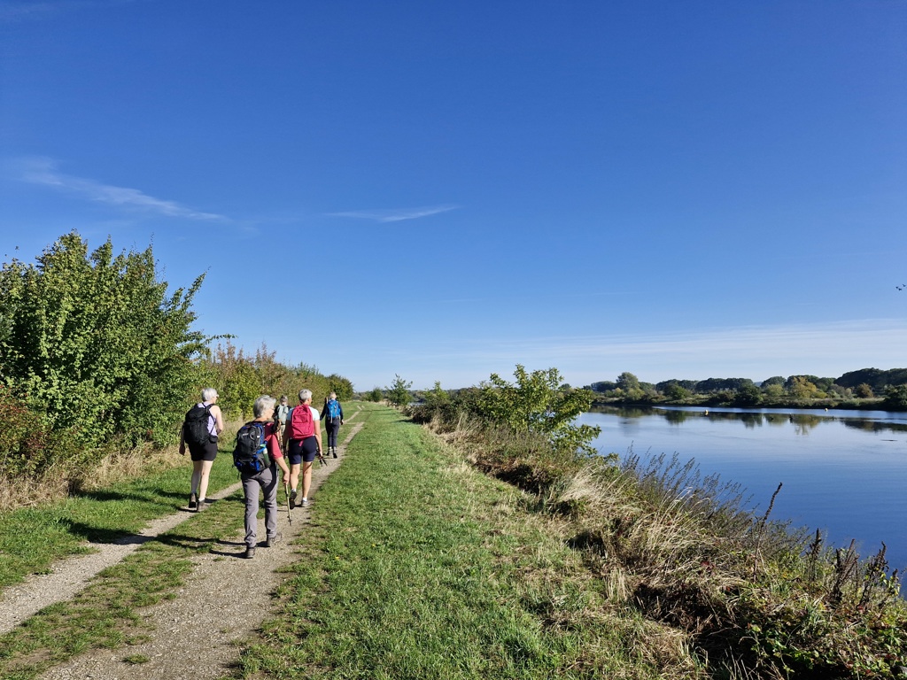 Wandelaars op een dijkpad langs een rivier in Nederland tijdens de Dutch Mountain Trail wandelvakantie.