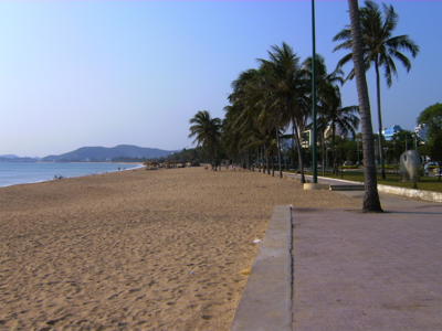 Zandstrand met palmbomen en boulevard in Nha Trang, Vietnam.