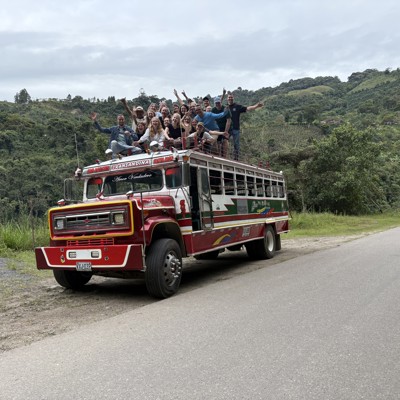 22-35ers reis Colombia: groep reizigers op het dak van een kleurrijke bus in de groene bergen.