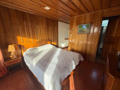 Slaapkamer met tweepersoonsbed en houten wanden in Hotel Los Cipreses, Costa Rica.