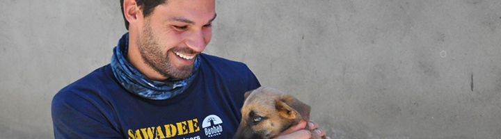 Reisbegeleider Gregory in Guatemala met een pup op schoot.