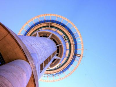 Sky Tower in Auckland, Nieuw-Zeeland, gezien van onderaf tegen een heldere blauwe lucht.