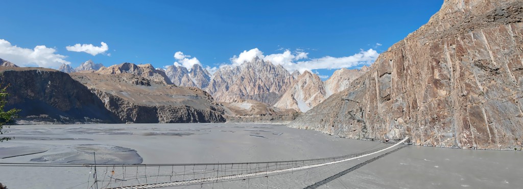 Hangbrug over een brede rivier met ruige bergtoppen in Baltistan en Hunza, Pakistan.