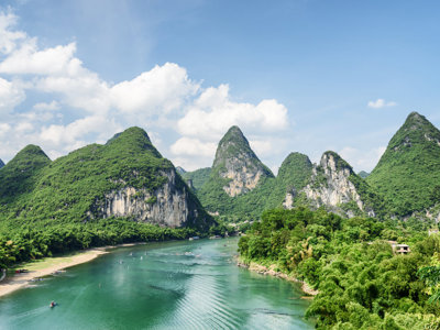 Karstbergen langs de Li-rivier bij Guilin, China, onder een blauwe lucht met wolken.