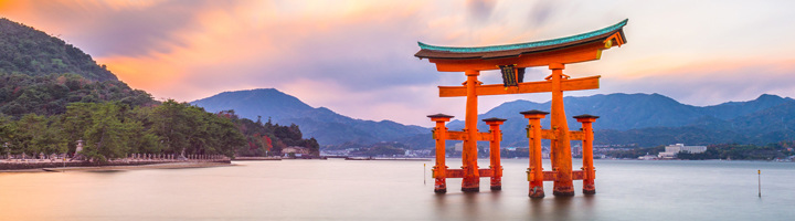 Rode torii-poort in zee bij zonsondergang, een iconisch Japanse bezienswaardigheid.