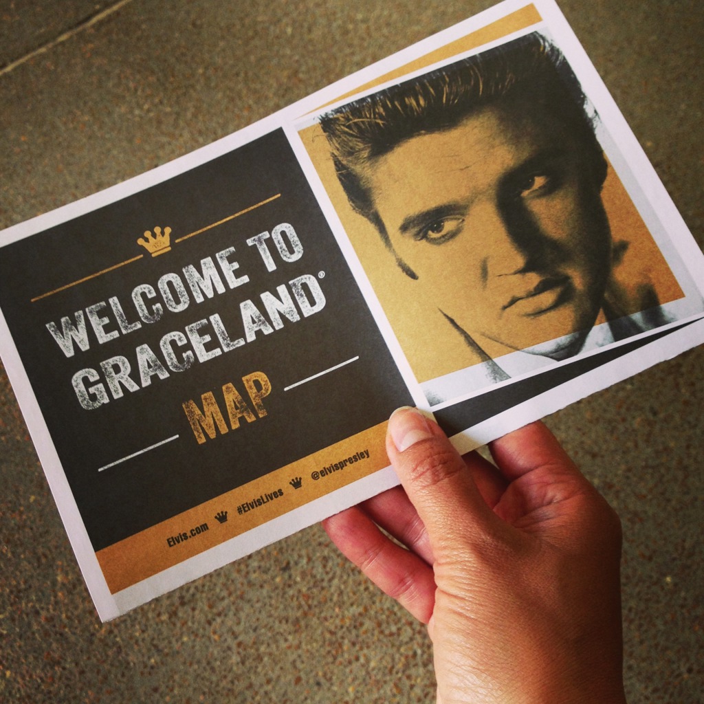 Hand houdt “Welcome to Graceland” plattegrond vast met portret van Elvis Presley, stop tijdens rondreis door de Verenigde Staten.