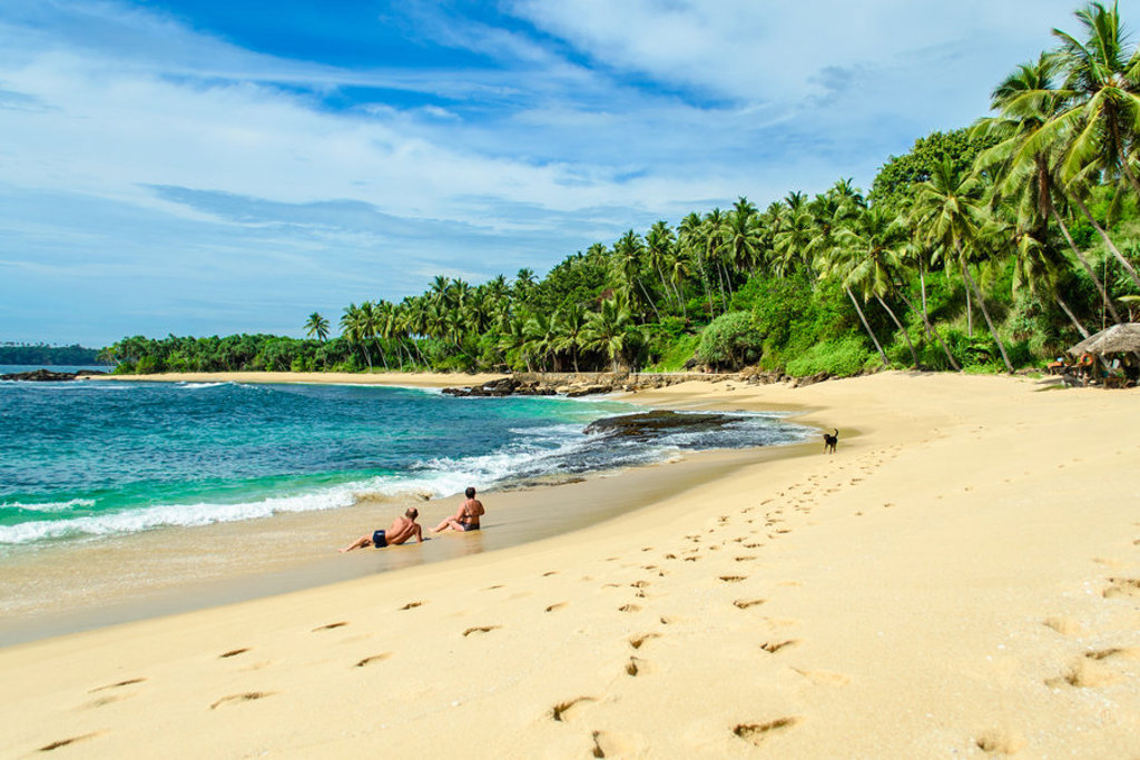 Tropisch zandstrand in Sri Lanka met palmbomen en turkoois water, populair strandmoment tijdens familiereis.