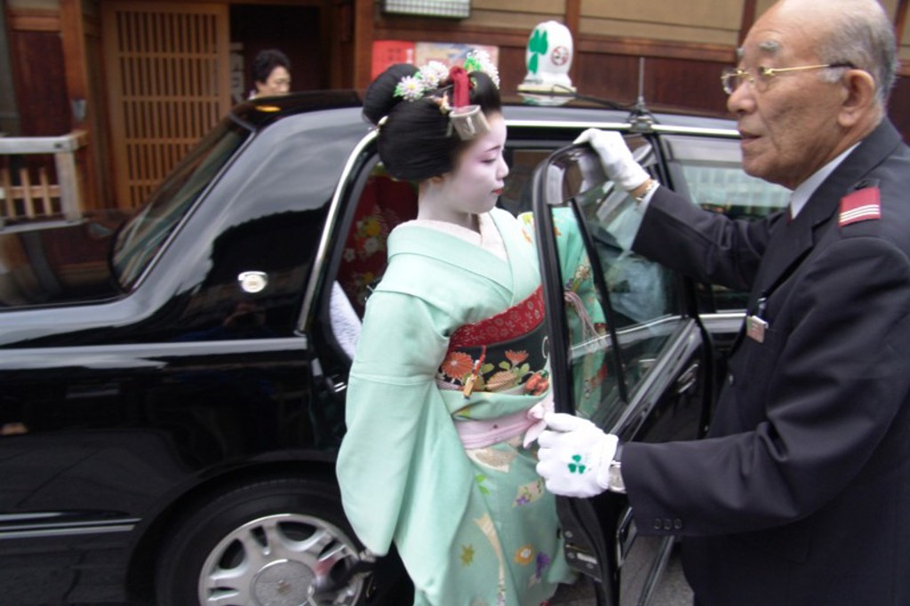 Geisha in kimono stapt in taxi in Japan tijdens een groepsrondreis Japan.