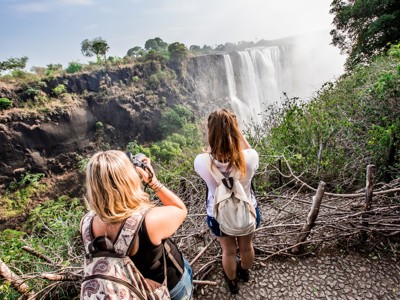 Reizigers fotograferen de Victoria Falls vanaf een uitkijkpunt langs de route Windhoek–Victoria Falls in Zuidelijk Afrika.