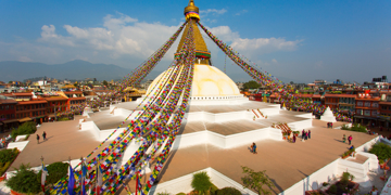 Boudhanath-stoepa in Kathmandu met kleurrijke gebedsvlaggen en uitzicht over de stad.