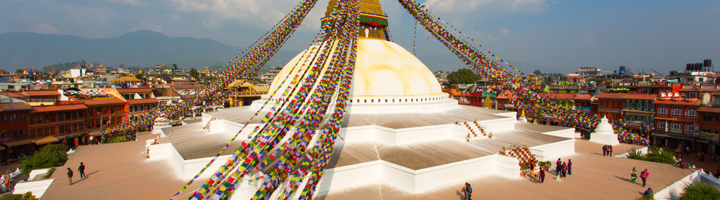 Boudhanath-stoepa in Kathmandu met kleurrijke gebedsvlaggen en uitzicht over de stad.