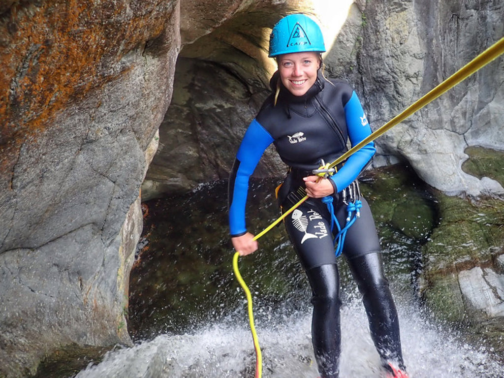 Canyoning in de Pyreneeën bij Canigou, Frankrijk: deelnemer in wetsuit en helm daalt af langs een waterval.