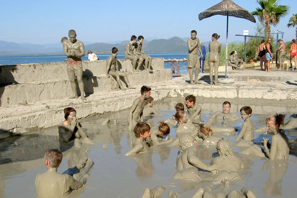 Gezinnen nemen een modderbad in een natuurlijke kleipoel aan zee in Zuid-Turkije.