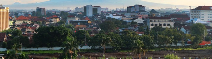 Skyline van Yogyakarta met treinspoor en de vulkaan Merapi op de achtergrond.