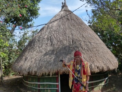 Man in traditionele kleding bij een rond huis met rieten dak op Sumba tijdens de route Timor, Sumba & Bali.