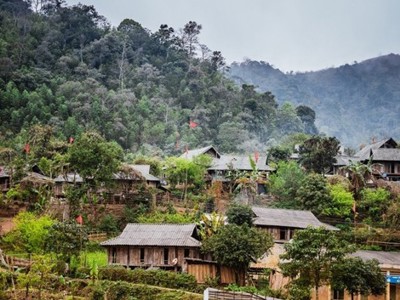 Bergdorp met houten huizen tussen groene heuvels in Noord-Vietnam, onderdeel van de Route Vietnam.