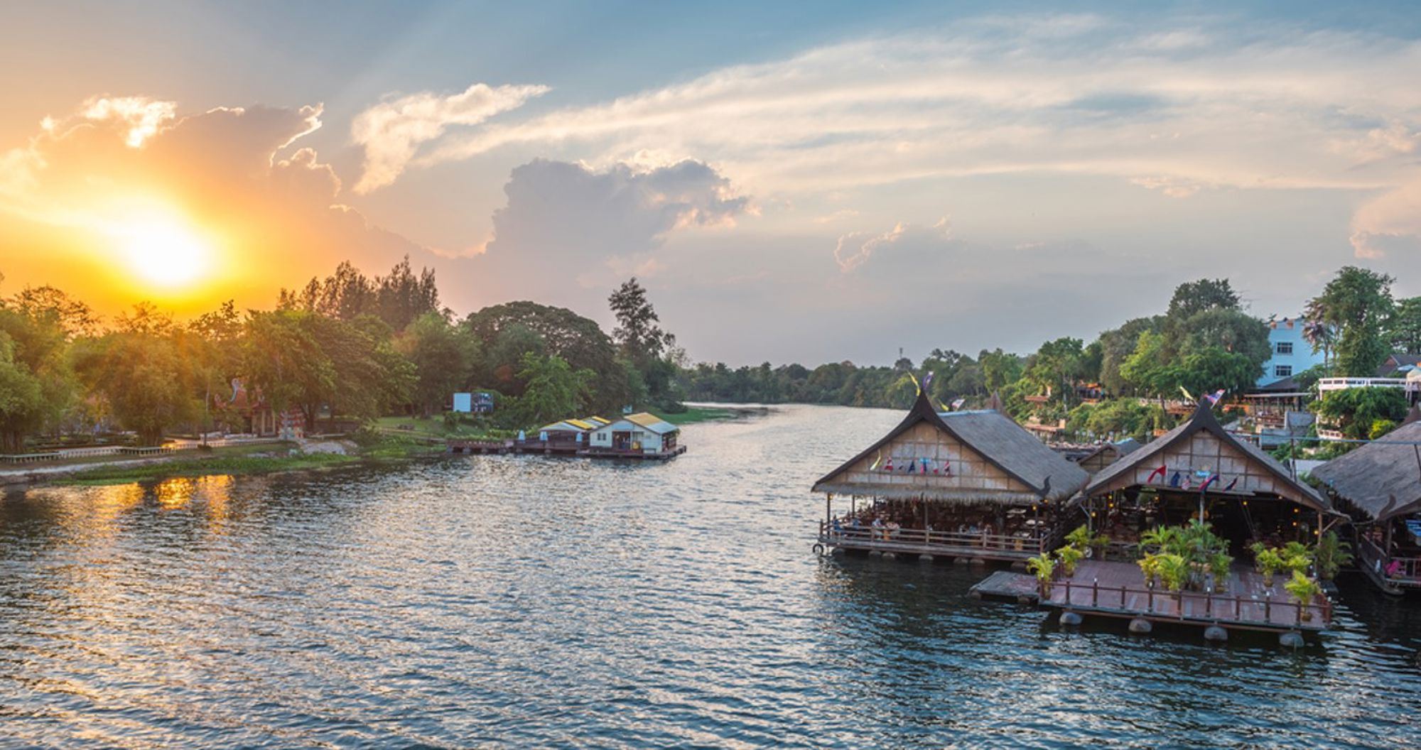 Drijvende restaurants aan de rivier bij zonsondergang in Kanchanaburi, Thailand.