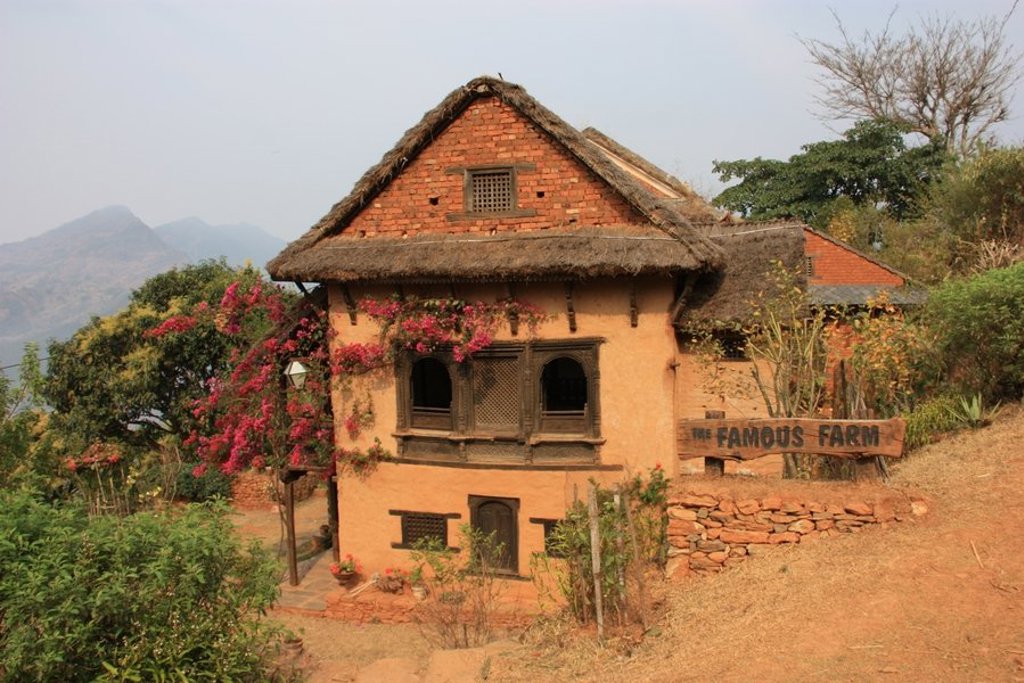 Traditionele boerderij in Nepal met rieten dak en bloemen, tijdens een groepsrondreis.