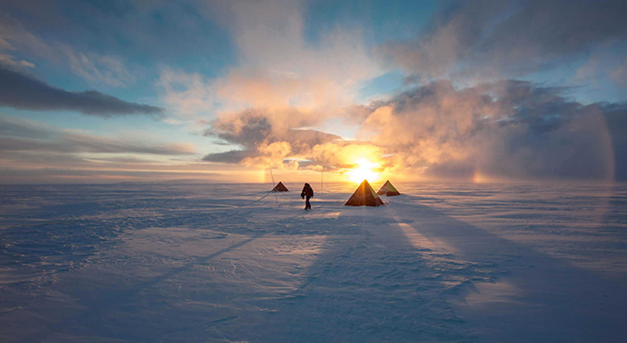 kamperen-zuidpool Expeditiekamp met tenten op een besneeuwde vlakte bij zonsondergang.