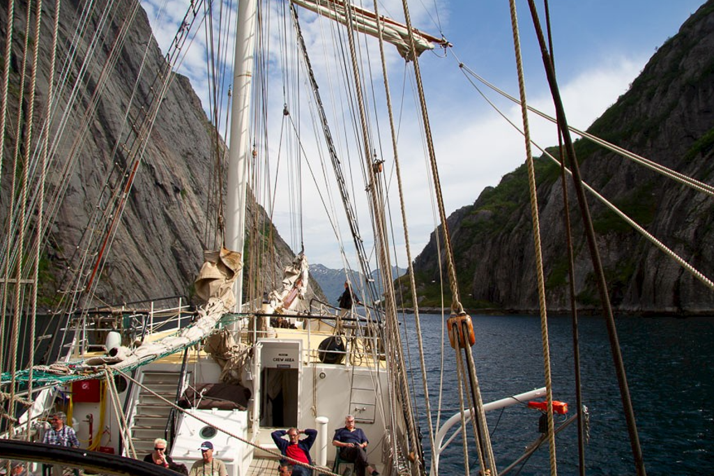 Zeilboot in een fjord bij de Lofoten, Noorwegen, met steile rotswanden en helder water.