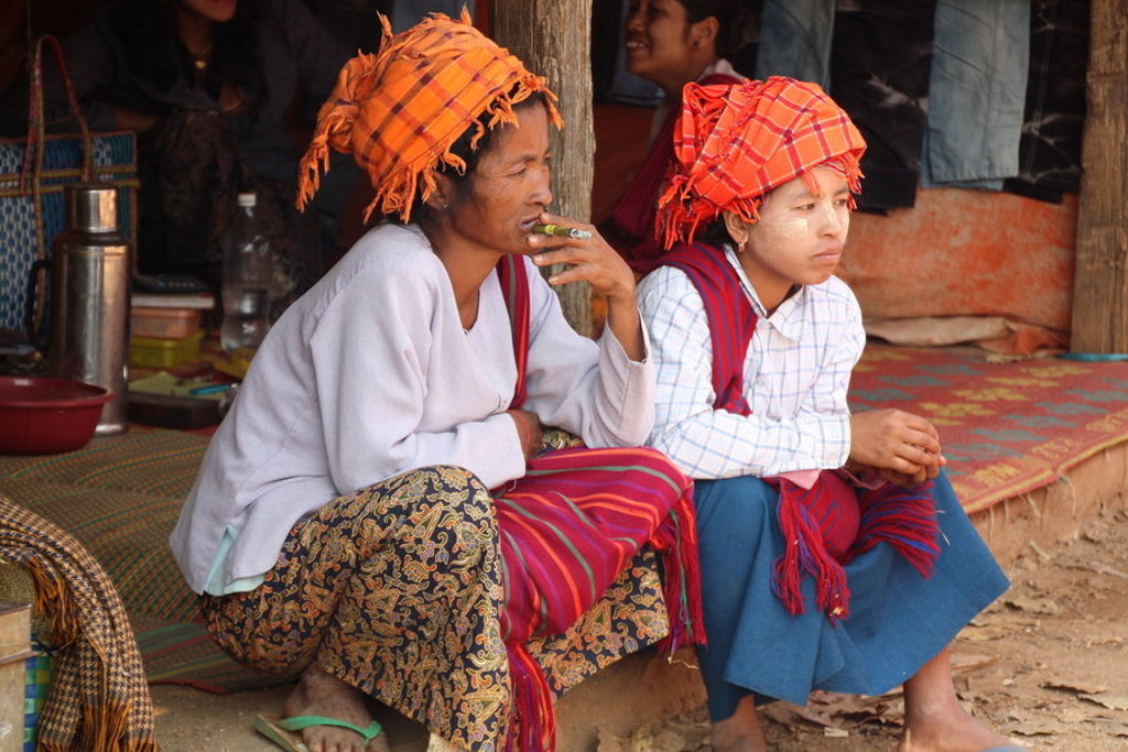 Twee vrouwen met traditionele hoofddoeken zitten bij een marktstalletje in Myanmar tijdens een groepsrondreis.